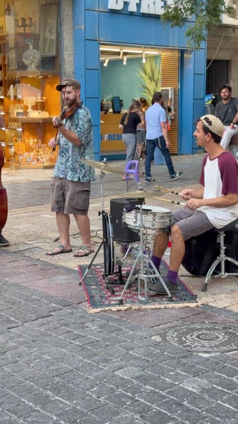 Two street musicians — a violinist and a drummer — performing for passers-by on Ben Yehuda Street, Jerusalem